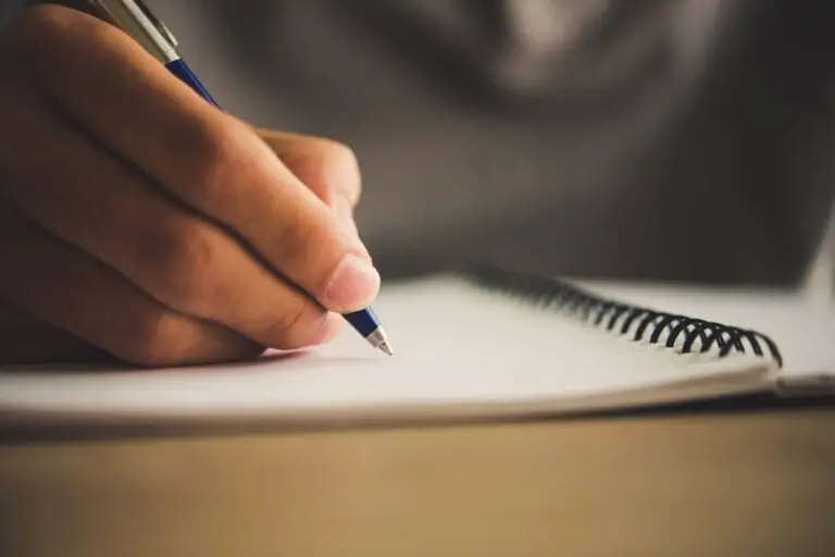 Someone writing a letter in a lined paper notebook
